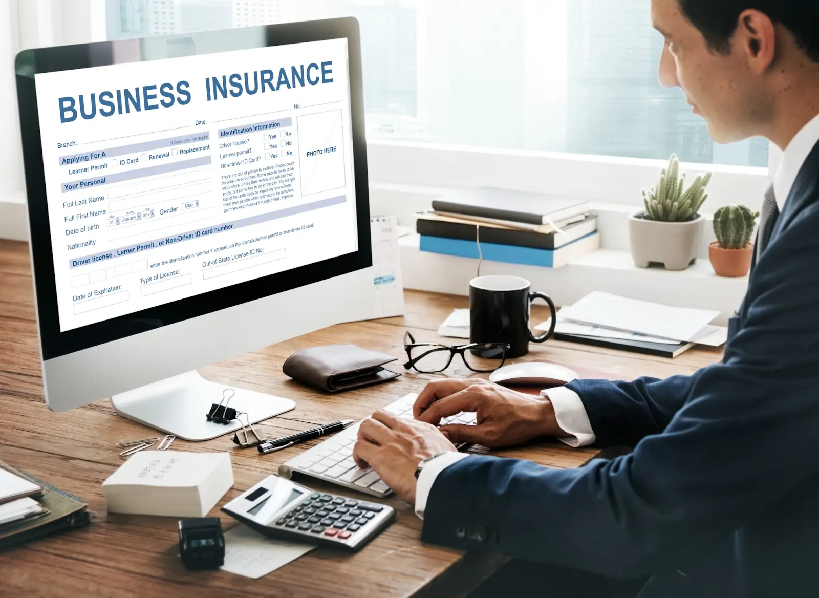 A business professional filling out an insurance form on a desktop computer at the office.